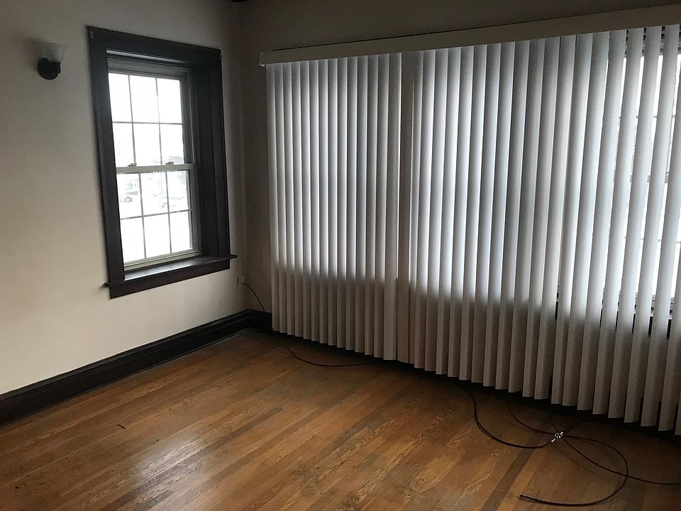 Living room includes hardwood flooring and 2 scounces on wall and new vertical blinds
