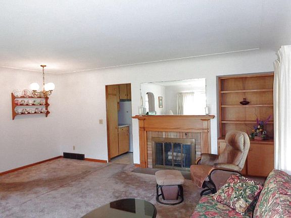 The other end of the living room has a fireplace,  built-in cabinet and dining area.