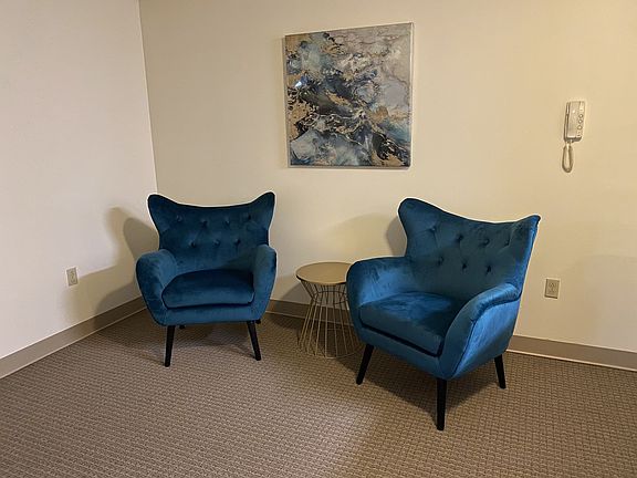 Living Room With 2 Wingback Blue Velvet Chairs And An Abstract Painting