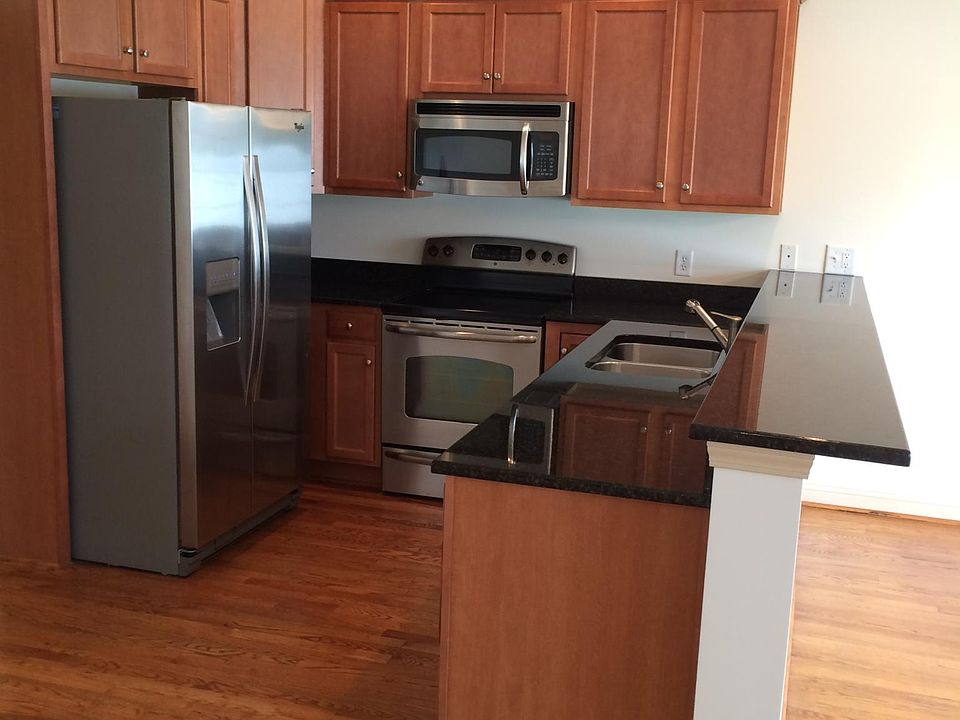 Kitchen with granite countertops, stainless steel refrigerator, stove, microwave and dishwasher. Hardwood floors.