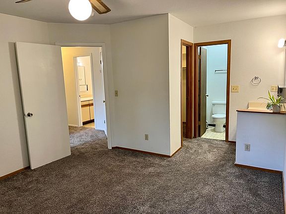 This is the main bedroom, looking out to the hallway (left) and to the walk-in closet (middle door) and bath (right door). Sink and mirror are behind the half wall on the right.