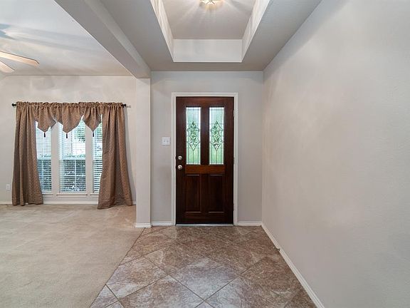 A beautiful leaded glass door opens into a classic entryway with tray ceiling and ceramic tile flooring!