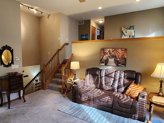 View from the fireplace, of the kitchen to the left, stairs down to the front hall, stairs up to the loft, and upstairs hallway to bedrooms.