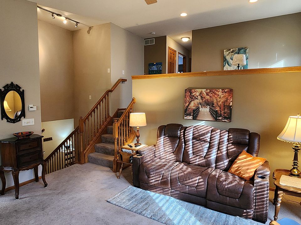 View from the fireplace, of the kitchen to the left, stairs down to the front hall, stairs up to the loft, and upstairs hallway to bedrooms.