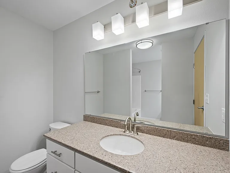 Modern bathroom featuring a sleek countertop, large mirror, and stylish lighting fixtures. Modern bathroom featuring a sleek countertop, large mirror, and stylish lighting fixtures.