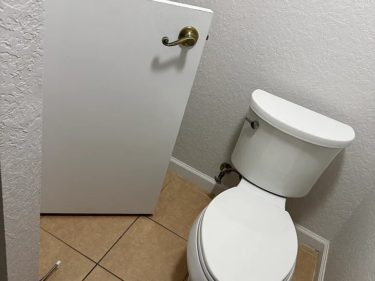 Toilet for guests with a closet under the stairs for travel bags.