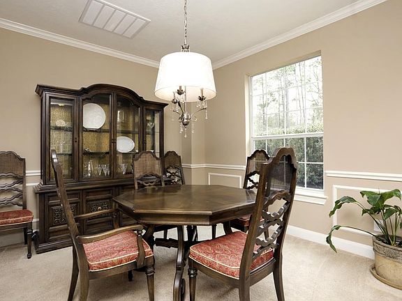Formal dining room is adorned with soothing color scheme, designer molding, stunning light fixture.