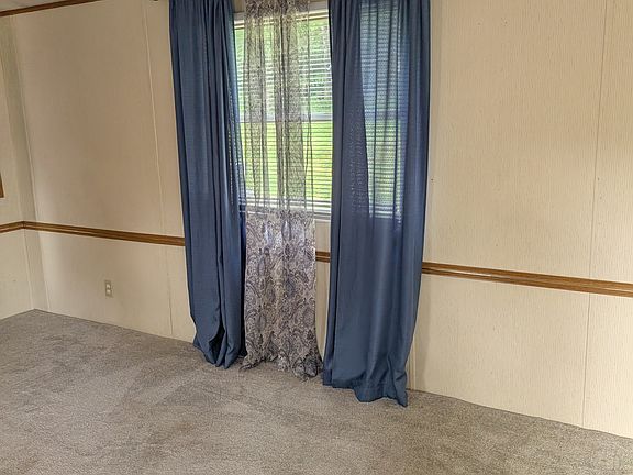 View of carpet and ivory colored walls with chair rail in living room.