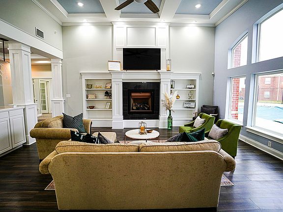 Kick back and connect in the bright and inviting resident lounge at The Bristol, featuring cozy seating, a fireplace, and views of the outdoor pool.