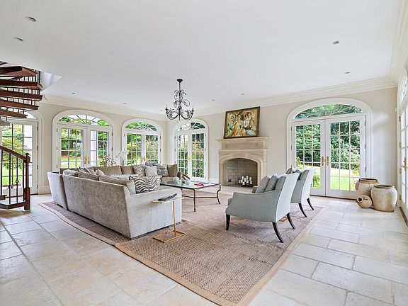Formal garden room with walls of glass and seven sets of curved French doors leading to the spectacular gardens, stone patios, pool, and tennis court.