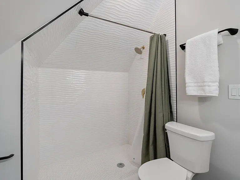 Walk-in shower with textured tile surround, rain-style showerhead, and clean finishes for easy daily use.
