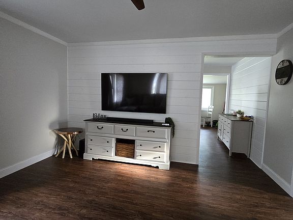Living room with ceiling fan, 65" Samsung TV, Samsung sound bar w/subwoofer, desk.
