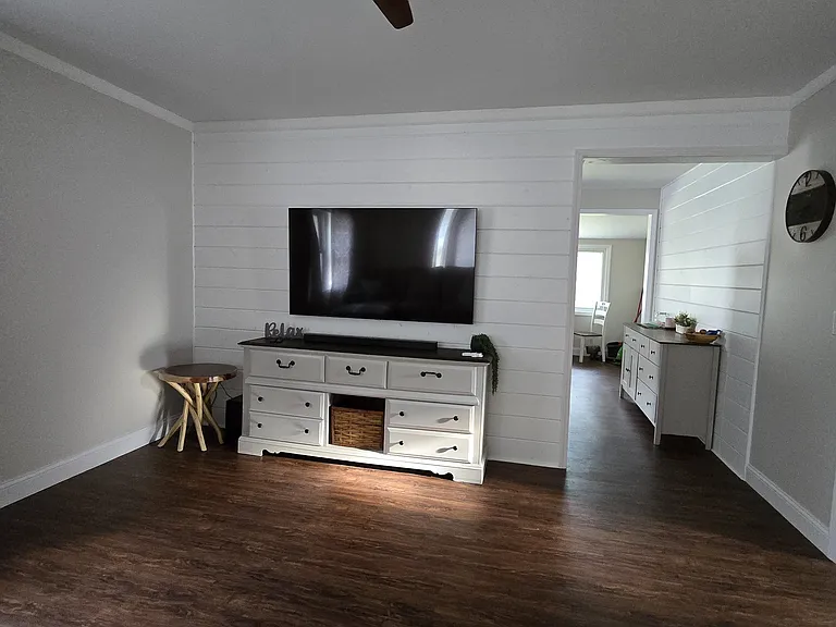 Living room with ceiling fan, 65" Samsung TV, Samsung sound bar w/subwoofer, desk.