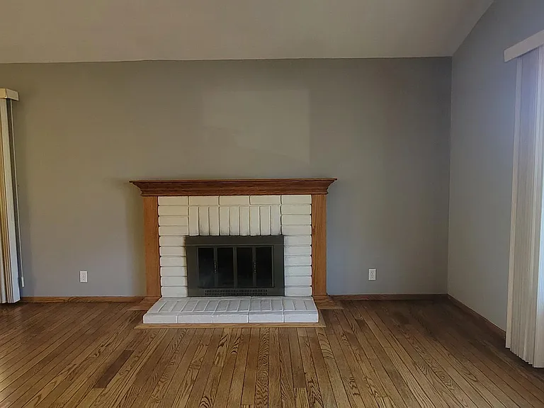 Warm living room featuring hardwood floors and a cozy fireplace.