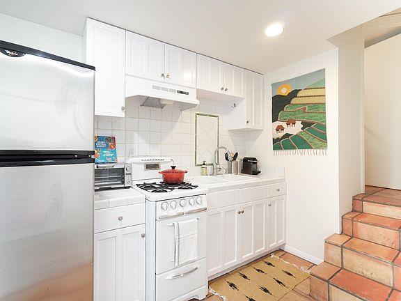 Compact kitchen with classic vintage stove, stainless fridge, Breville smart oven, Nespresso machine, dishes, etc,