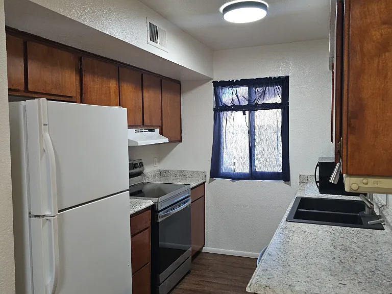 Kitchen includes electric range, refrigerator, dishwasher and counter top microwave.