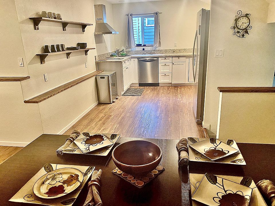 View of fully stocked kitchen (new appliances including Multi-purpose countertop oven/air fryer/toaster/slow cooker etc. And two burner induction stove top) from dining and granite bar area looking over living room- TV can be viewed from dining area