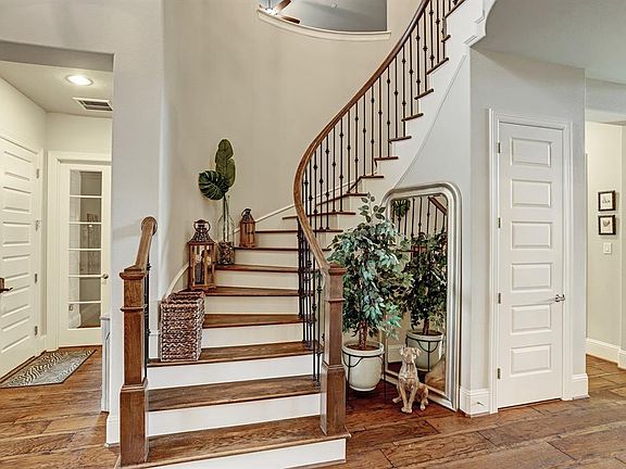 This grand curved staircase located in the foyer leads up to the second level. The staircase has hardwood treads and a wrought iron and wood banister. A closet is located under the staircase.