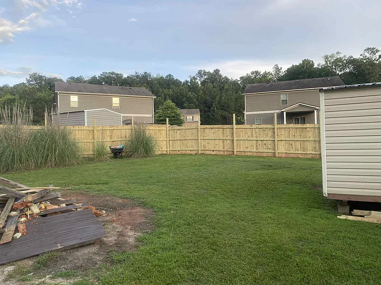 Back yard with new privacy fence and a shed. The burn pile is now gone, and grass has been seeded.