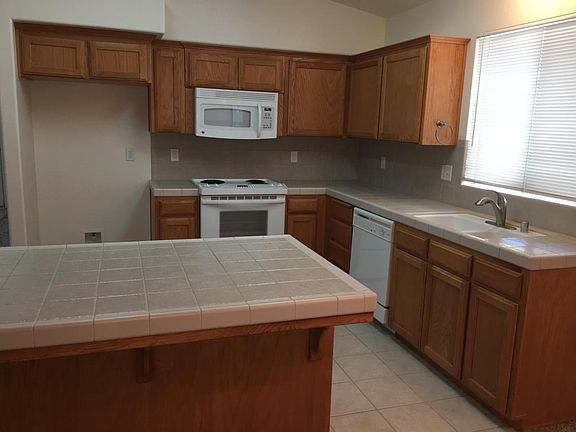 Kitchen with oak cabinets and tile countertops, oven/range, dish washer, microwave.