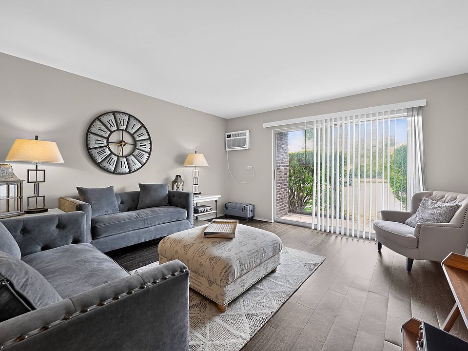 Gather in a comfortable living room featuring grey couches and a statement wall clock at Renaissance at Carol Stream in Carol Stream, IL.