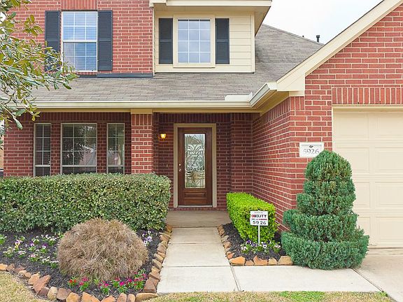 A warm & inviting entry with brick column accents and a gorgeous wood stained & leaded glass front e