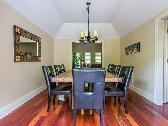 Large dining room with vaulted ceiling and dental molding opens through French doors to back deck