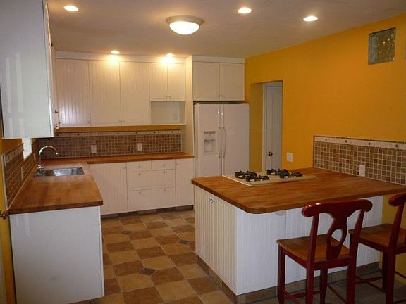 Updated kitchen with butcher block counters, custom tile work and a useful eating bar.