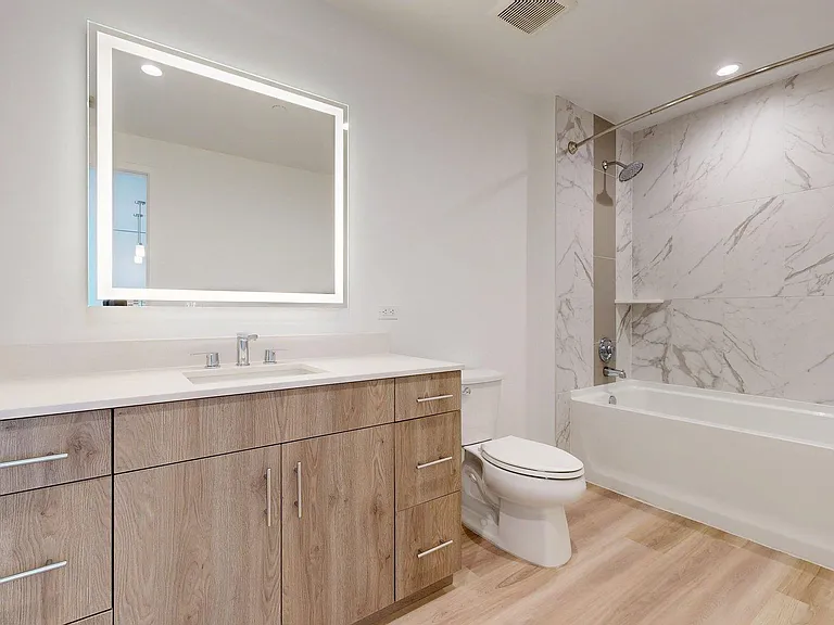 Apartment Bathroom with large soaking tub, LED vanity mirror and Wood Style Flooring.