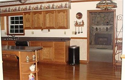 kitchen with oak hardwood flooring and entrance to family room with gas fireplace