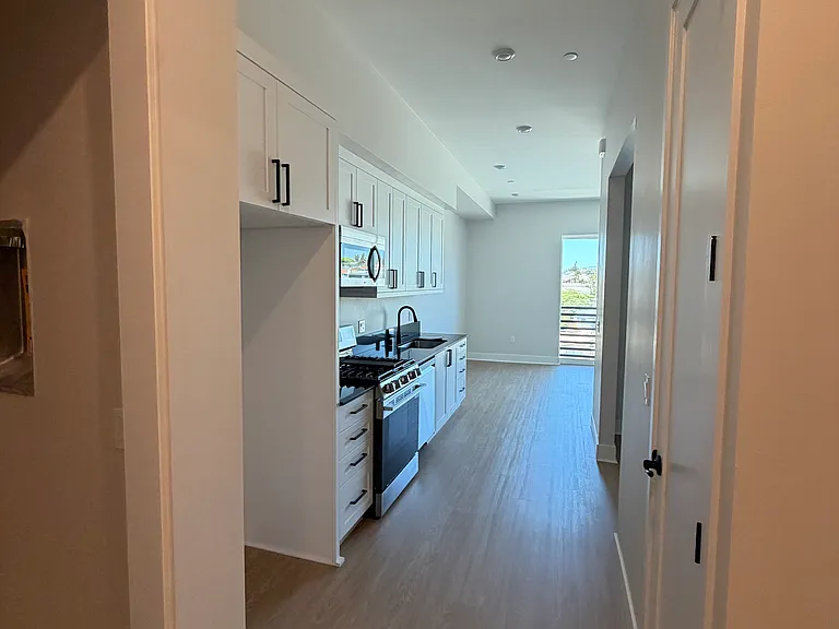 View from front door. In unit washer/dryer to left, bathroom on right, looking down main hallway of flat.