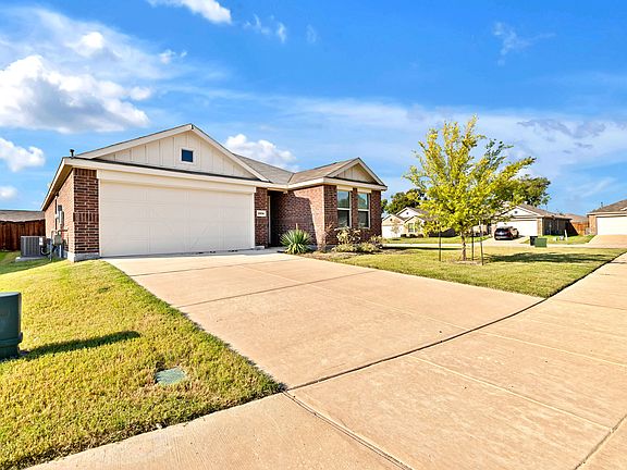 Ranch-style house featuring an attached garage, brick siding, and driveway
