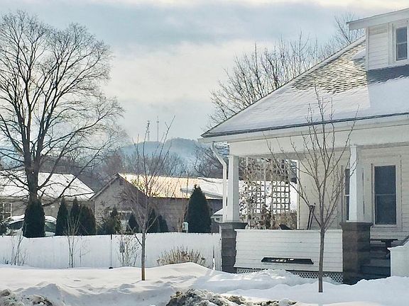 View of fenced side yard with white-cedar arborvitae and mountains