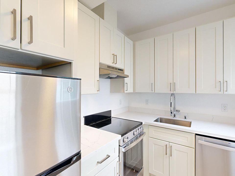 Modern kitchen featuring stainless steel appliances, quartz countertops, and cabinetry with sleek handles. Bright and stylish design.