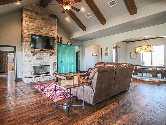 Open living area with hardwood floors and high, beamed ceiling.