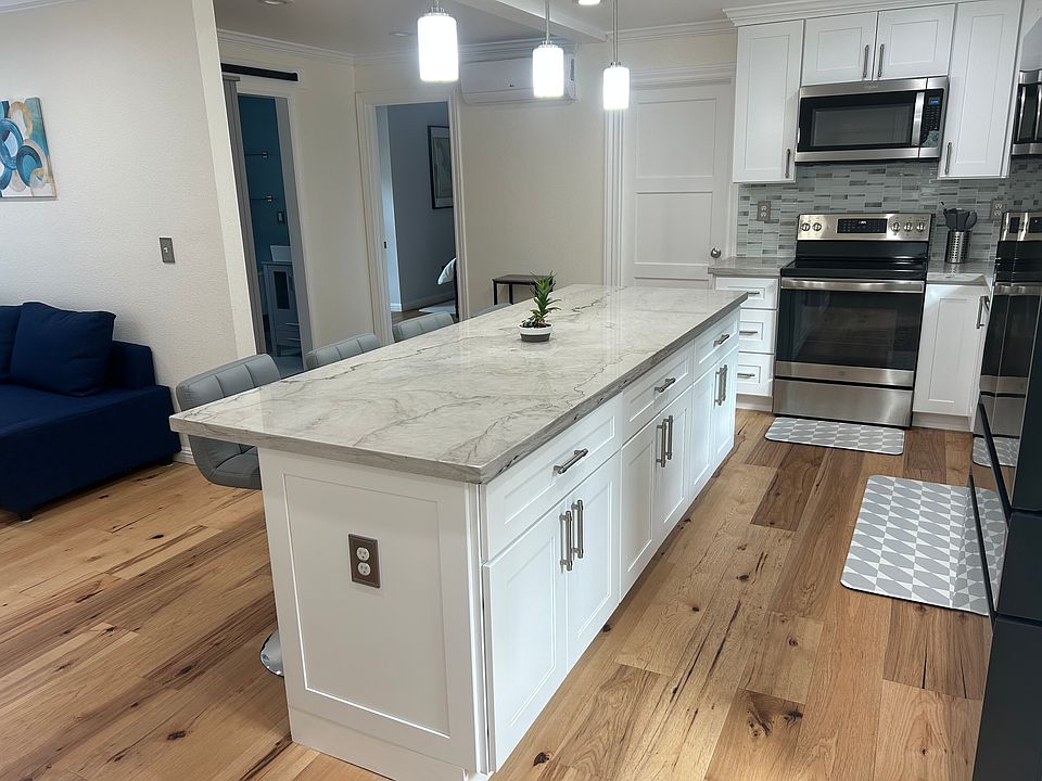 Apartemnt interior as seen from the entry door. Brand new kitchen appliances with beautiful island. Sitting area to the left and bedrooms with queen beds and bathroom can be seen.