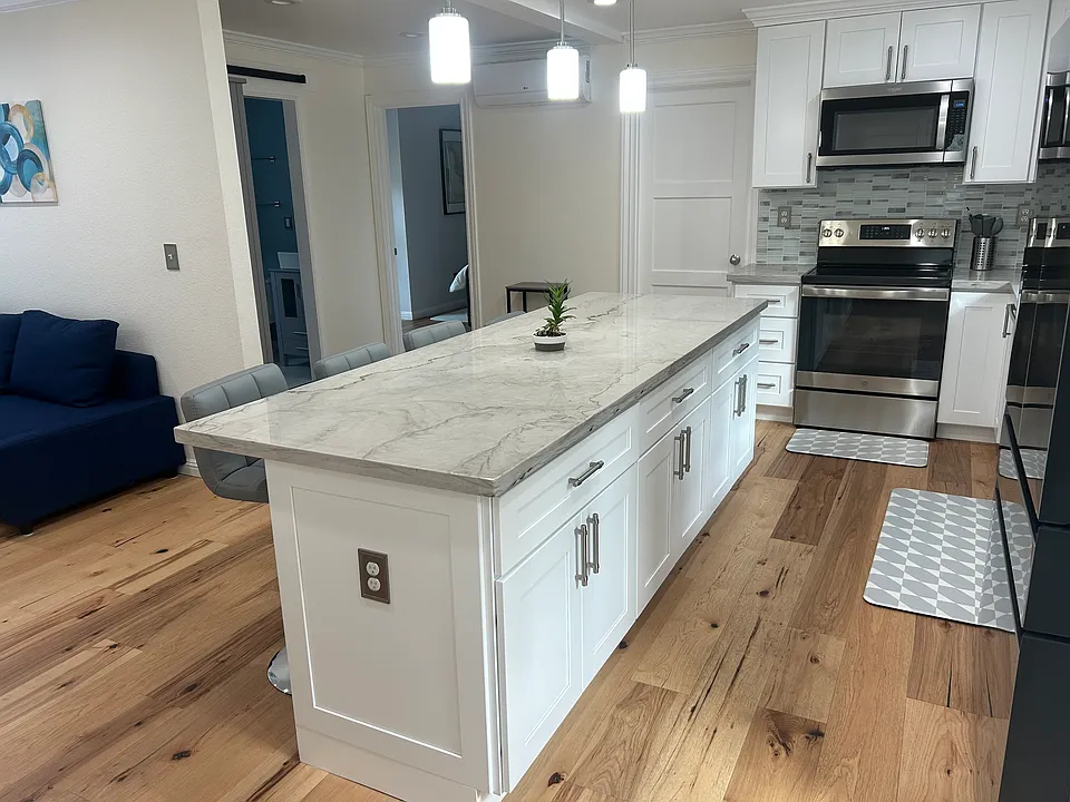 Apartemnt interior as seen from the entry door. Brand new kitchen appliances with beautiful island. Sitting area to the left and bedrooms with queen beds and bathroom can be seen.