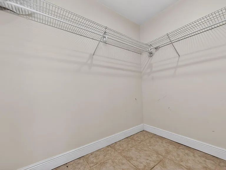 Spacious walk-in closet with wraparound wire shelving for efficient hanging and storage organization.