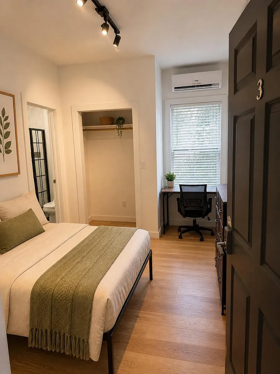Furnished bedroom with dedicated desk area, window blinds, and open closet storage; includes mini-split A/C for comfort. - 9th Ave N