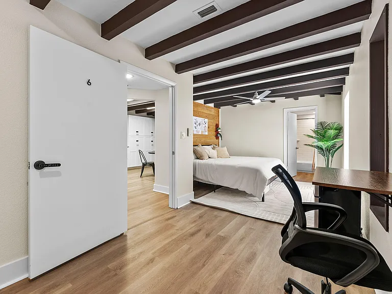Private bedroom with exposed beam ceiling, work desk, and adjacent bath access for an easy daily routine.