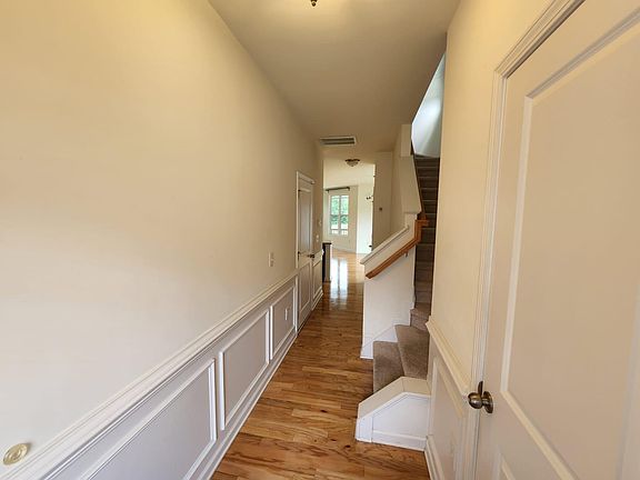 Entry foyer connecting stairs and main floor. Door on right is powder room, door on left is to the garage