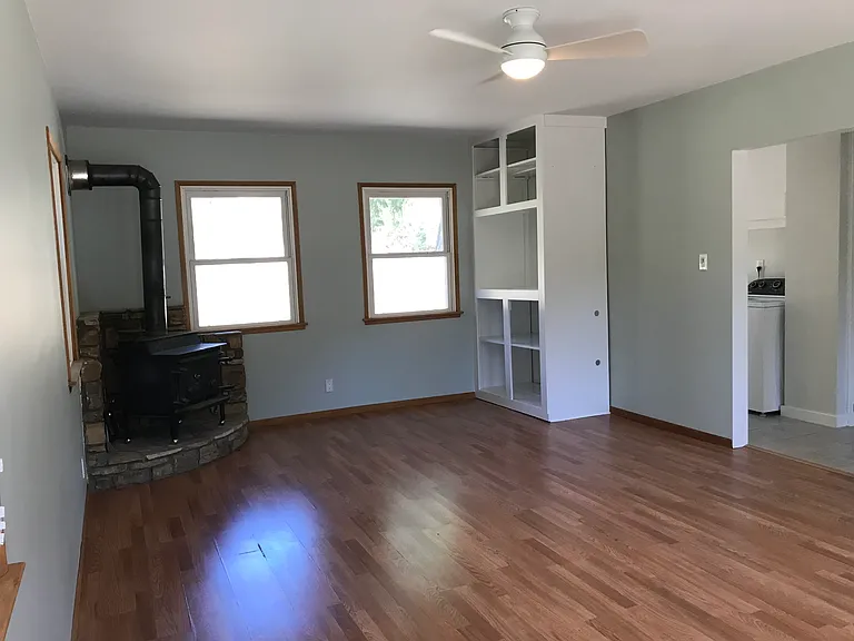 Large living room with plenty of windows for cross ventilation, built in entertainment center and wood stove.