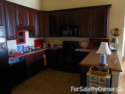 Entering Kitchen from Garage and Laundry
						:
						L-R: Refrigerator, washer, sink, range, microwave, bar, Dining Area (not seen).