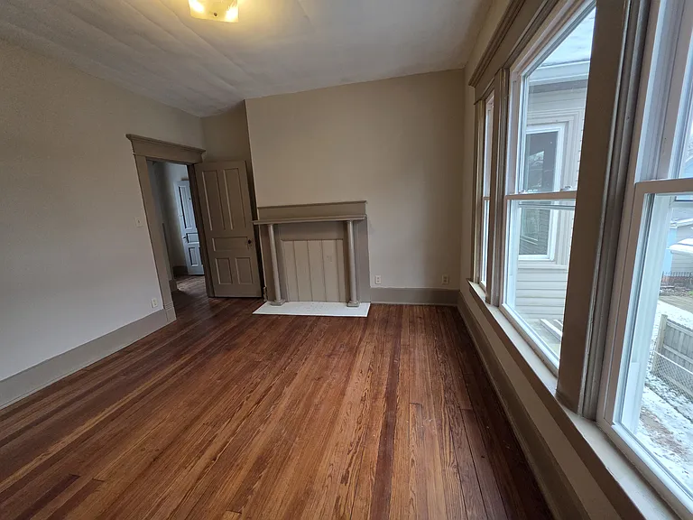 View from the closet in the 2nd bedroom, looking at the decorative fireplace, door and windows.