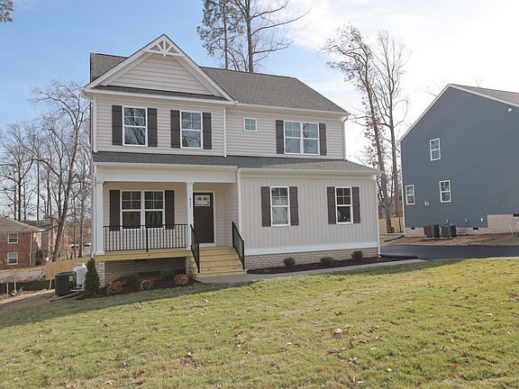 A modern two-story house with a front porch in Poplar Village, nestled on a grassy lawn near Lot 31s