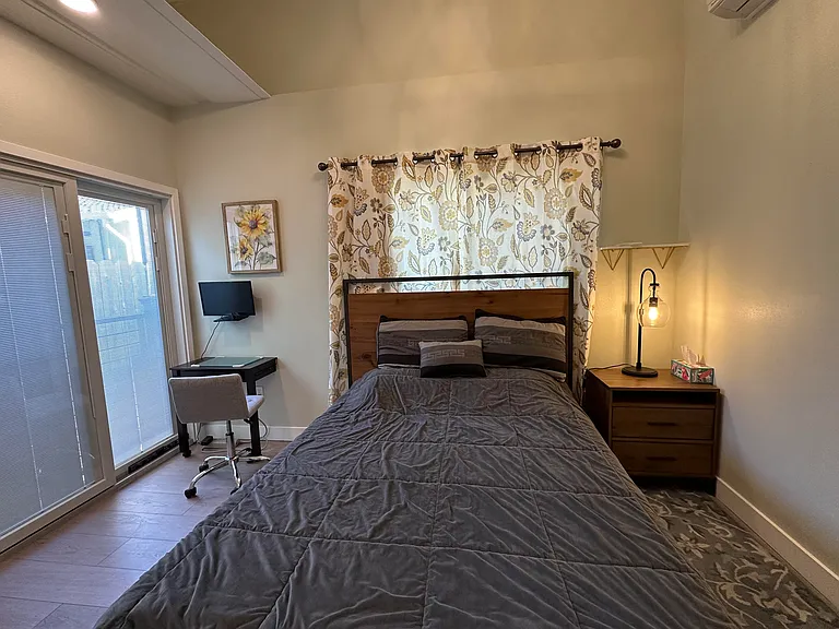 Bedroom #1 with queen-sized bed, nightstand and small desk and chair with wall mounted computer monitor