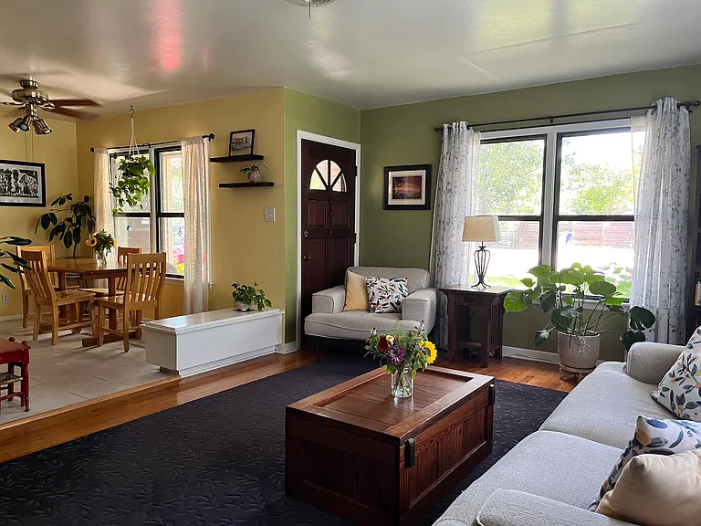 Living room with view of dining area; the white bench near the door opens for storage