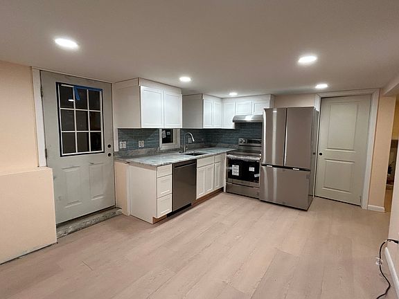 Kitchen opens to living room. Door leads to utility/laundry room with storage.