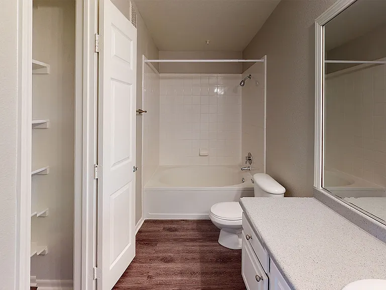 Apartment bathroom with large soaking tub and wood-style flooring.
