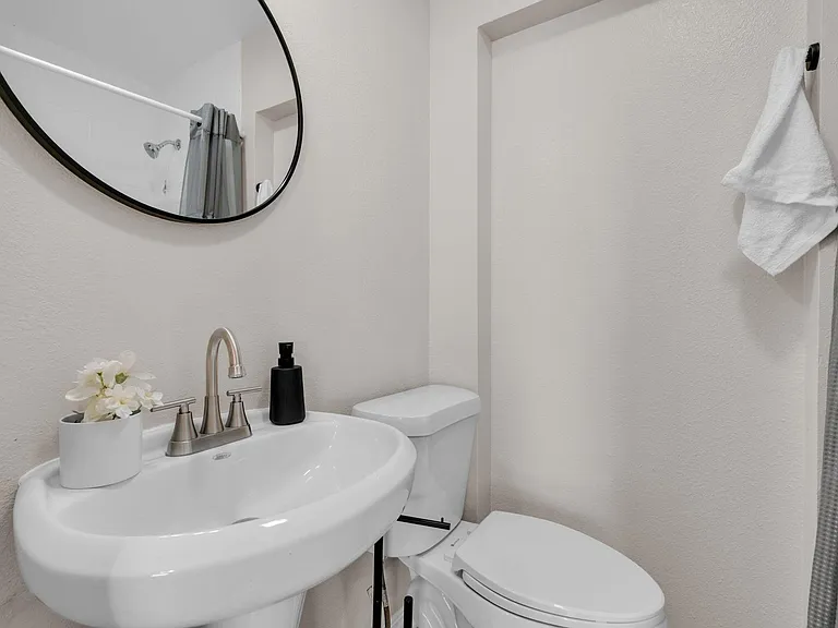 Bathroom with pedestal sink, round mirror, and tub/shower combo with curtaineasy-care layout for everyday use.